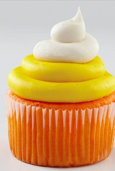 an orange cupcake with white frosting and icing sitting on top of it