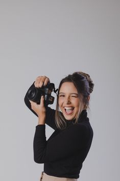 a woman holding up a camera and smiling