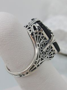 Black Camphor Glass Solid Sterling Silver Ring Grace Design#D233 This is a lovely antique Edwardian era inspired filigree ring. This gorgeous ring is created in stunning black camphor glass. The glass is embellished with a delicate floral filigree. The top of the ring holds a center set 1mm round cut gemstone (Choose from white Cubic Zirconia, lab created white Moissanite, or Natural/Genuine White Diamond). The black glass is 18mm x 19mm. The ring sits 18mm north-south and 10mm east-west on the Floral Filigree, Edwardian Style, Gem Diamonds, Gorgeous Ring, North South, Cubic Zirconia Rings, Edwardian Era, Edwardian Fashion, Old Hollywood Glamour