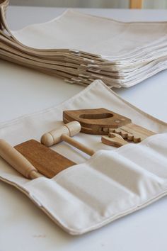 several wooden utensils are sitting on a white cloth with folded napkins in the background