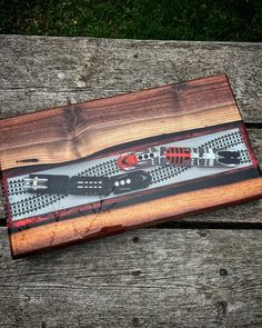 a wooden box with two knives in it on top of a wood table next to grass