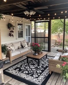 an outdoor living area with couches, tables and lights on the ceiling is decorated with potted plants