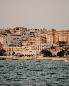 an old city sits on top of a hill next to the water with boats in it