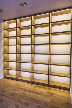 an empty bookcase in the corner of a room with wood floors and white walls