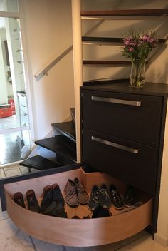 there is a shoe rack with shoes in the bottom drawer and a vase on top