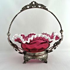 a pink glass bowl sitting on top of a metal stand