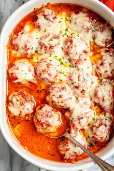 a white bowl filled with meatballs covered in sauce and parmesan cheese on top