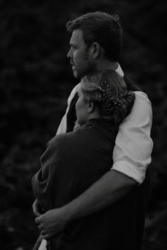 a man and woman embracing each other in black and white