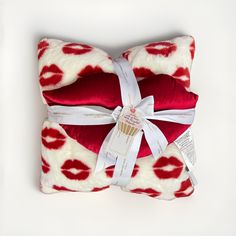 a red and white pillow with lipstick print on it, tied up to the side