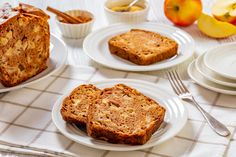 slices of banana bread on white plates with apples in the background