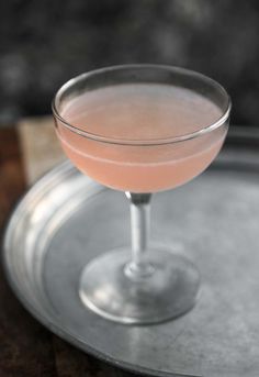 a pink drink in a coupe glass on a tray