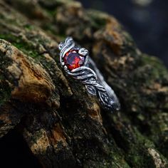 a red stone ring sitting on top of a tree branch