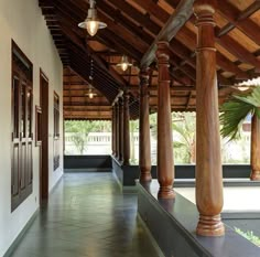 an outdoor covered walkway with columns and lights hanging from the ceiling, along with potted plants on either side