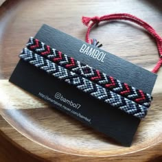 a black and red bracelet on top of a wooden plate