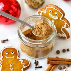 ginger spice in a glass jar next to cinnamon sticks and christmas decorations on a white surface