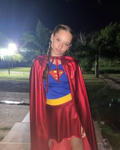 a woman dressed as a supergirl posing for a photo in the park at night