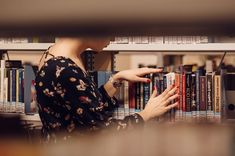 a woman looking at books in a library