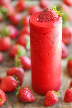 a red drink with strawberries scattered around it