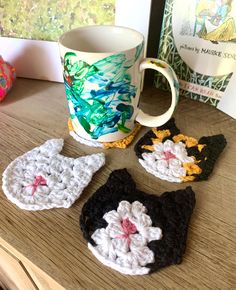 four crocheted coasters sitting on top of a table next to a coffee cup