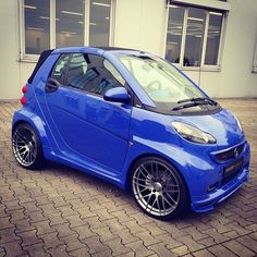 a blue smart car parked in front of a building