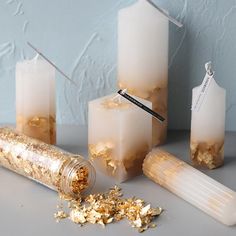 three candles with gold flakes on them and one candle has a straw sticking out of it