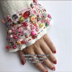 there is a woman's hand with red nail polish and beading on it