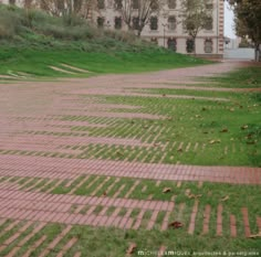 an empty brick path in front of a building with grass growing on the ground and steps leading up to it