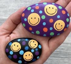 two rocks with smiley faces painted on them in the palm of someone's hand