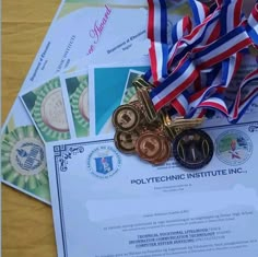 several medals are placed on top of a piece of paper with ribbons around it and some other items