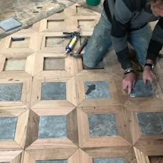 a man is working on wood flooring with tile and tools in the foreground