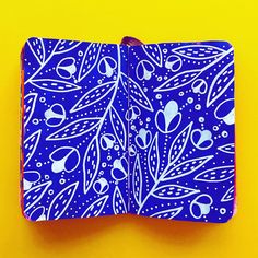 a blue and white patterned notebook sitting on top of a yellow surface with an orange edge