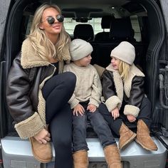 two women and one child sitting in the back of a van with their feet up