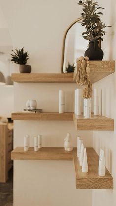 three wooden shelves with plants and candles on them in a room that has white walls