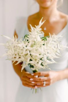 a woman holding a bouquet of white flowers