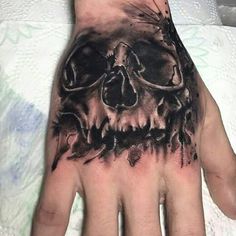 a man's hand with a black and grey skull tattoo on the middle of it