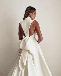 a woman in a white dress with a big bow on the back