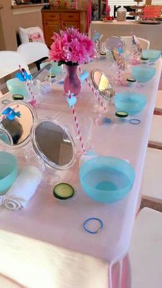 the table is set up for a party with pink flowers and blue dishes on it