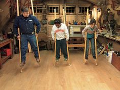 three people are working in a workshop with wooden floors and tools on the floor,