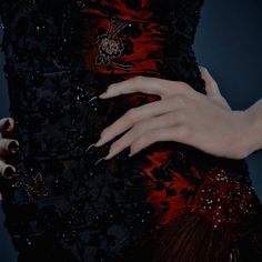 a woman's hand with black and red nail polish on her nails holding onto the dress