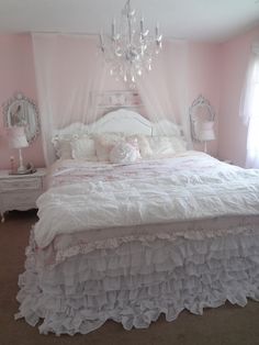 a white bed sitting in a bedroom next to a window and a chandelier