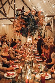 a group of people sitting around a table with plates and food on it in a tent