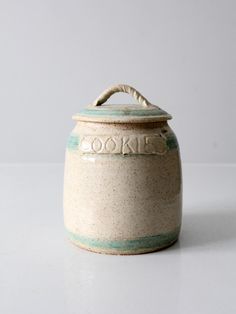 a ceramic cookie jar sitting on top of a table next to a white wall with the word cookies written on it