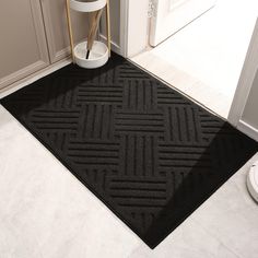 a black door mat in the corner of a room with a white toilet and chair