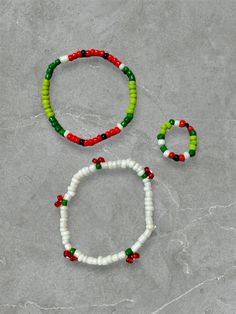 three bracelets with beads on top of a gray surface next to an orange, green and white beaded bracelet