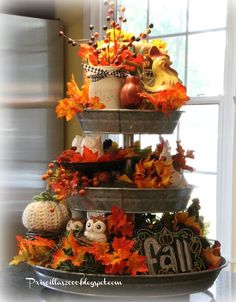 a three tiered tray filled with fall decorations