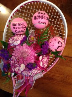 a tennis racquet with flowers and two pink balls that say the ball is in your cage