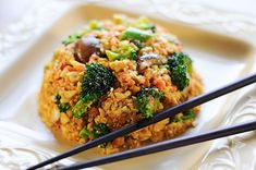 an image of some food on a plate with chopsticks in the foreground