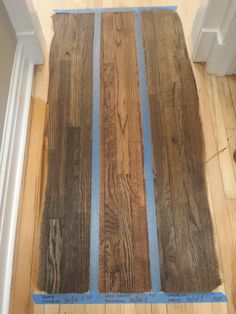 wood flooring being installed in a house with blue tape on the floor and white trim around it