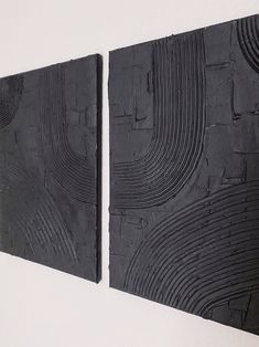 two pieces of black wood are hanging on the wall next to each other in an art gallery