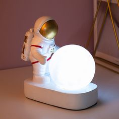 an astronaut is playing with a ball on a white surface in front of a purple wall